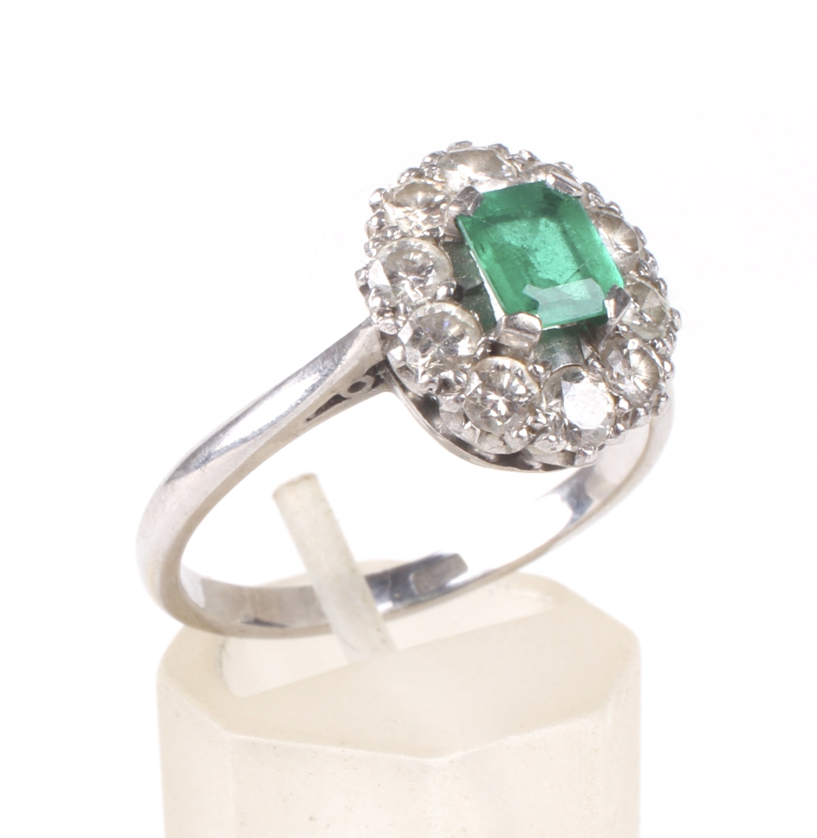 A mid 20th century white gold, emerald and diamond oval cluster ring.