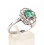 A mid 20th century white gold, emerald and diamond oval cluster ring.