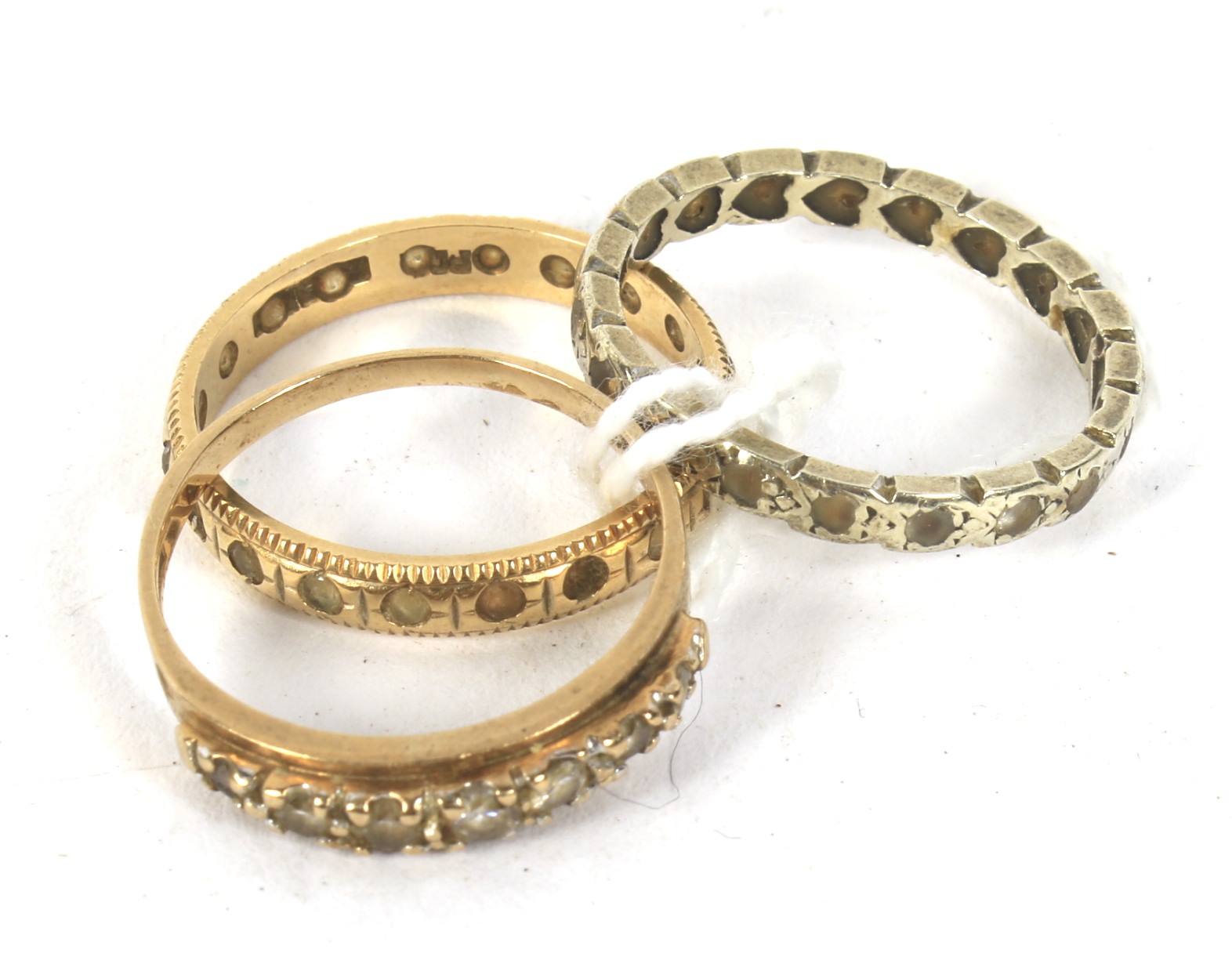 Three white and yellow metal rings. One set with stones, sizes N-O, 6.