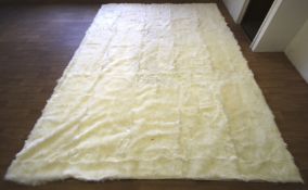 A large white goat fur rug. The natural growth direction of the fur giving a textured finish.