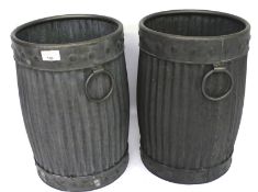 A pair of contemporary galvanised metal log bins in the form of barrels.