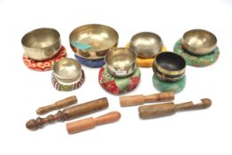 A collection of seven Tibetan singing bowls, with padded cushions and twelve strikers.