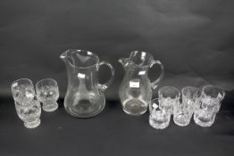 Three sets of three whisky tumblers and two pouring jugs.