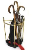 An early 20th century brass stick stand together with a selection of sticks and umbrellas.