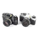 Two Olympus OM10 35mm SLR cameras. One black with a 50mm 1:1.