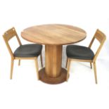 A contemporary oak circular breakfast table and two chairs.