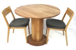 A contemporary oak circular breakfast table and two chairs.