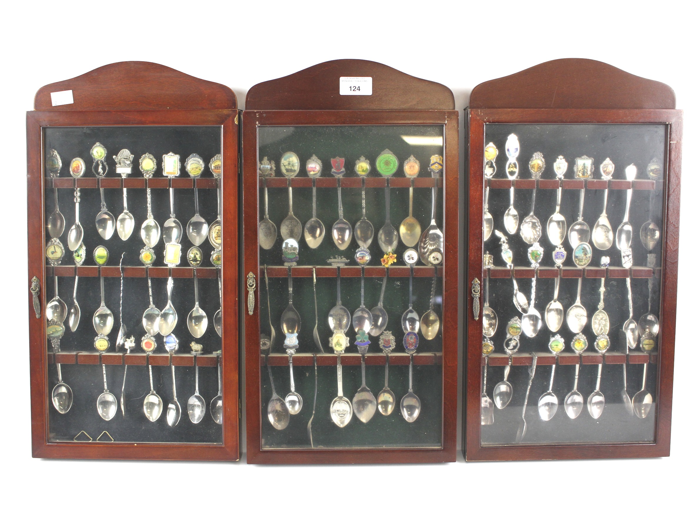 Three glazed wooden display cases containing a collection of souvenir spoons.