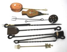 A collection of wrought iron fire tools, a bellows, a brass fork and other metalware.