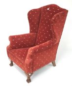 An upholstered wing backed armchair.