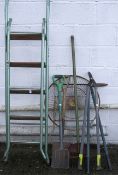 An assortment of garden tools, ladder and a small table.