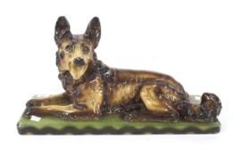 An Art Deco painted plaster model of an alsation dog on a green base. 56.