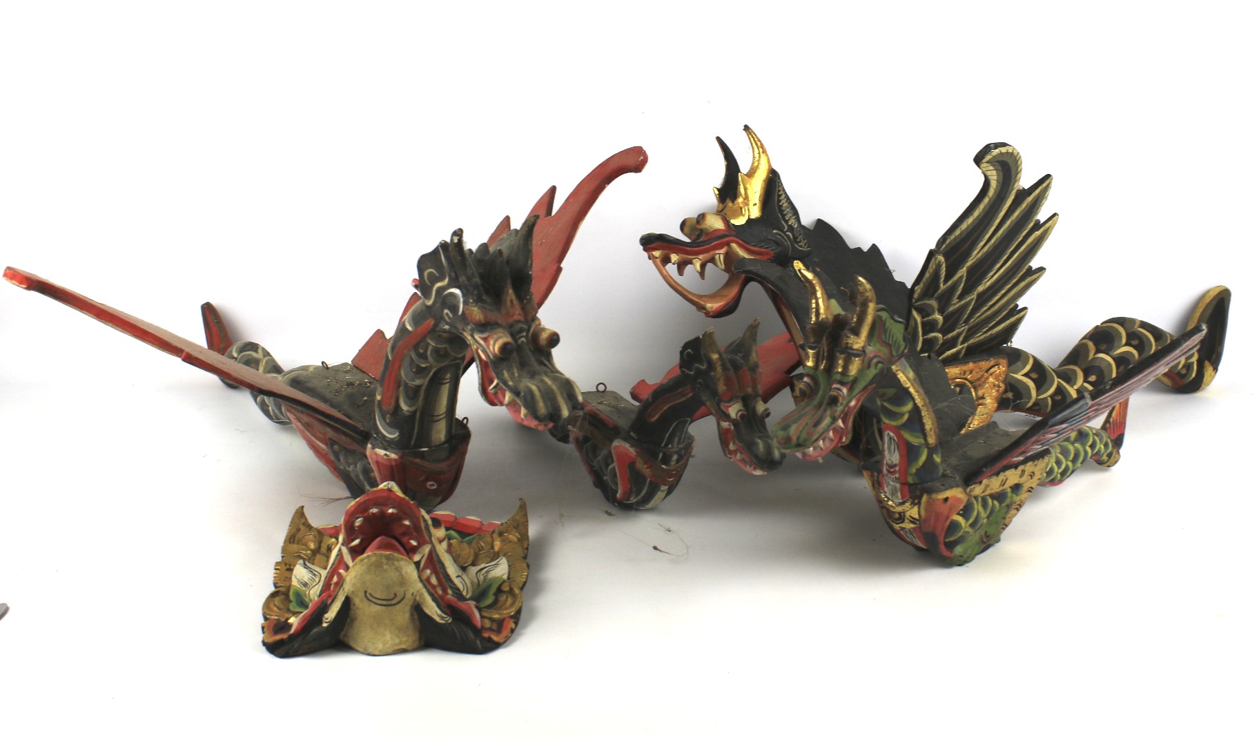 A collection of four painted Balinese carved wooden figures of dragons.