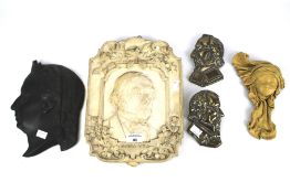An assortment of ceramic and cast metal profiles of historic individuals.