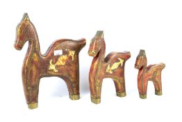 A set of three carved wooden stylised tribal figures of horses.