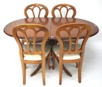 A contemporary wooden extendable dining table and four chairs.