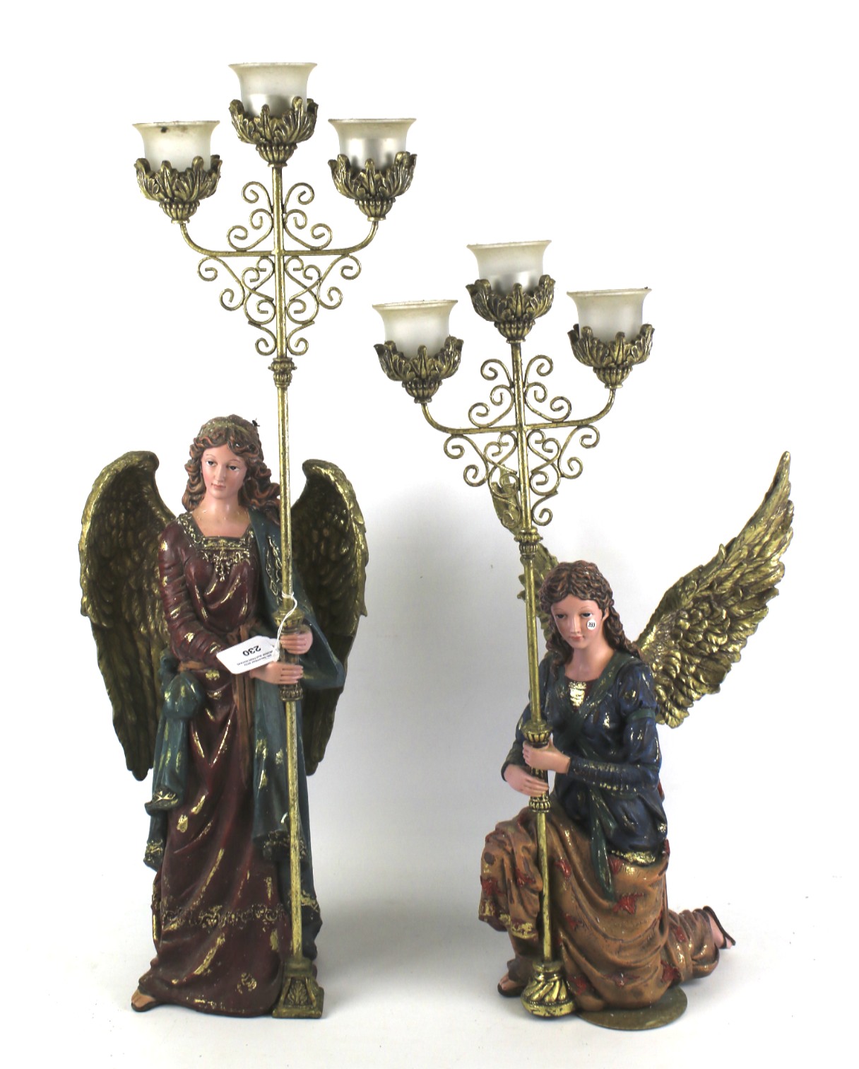 Two modern resin figures of angels, each holding three-pronged candelabras.