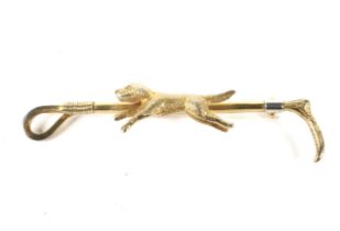 An early 20th century 9ct gold and platinum bar brooch. In the form of a walking cane and dog.