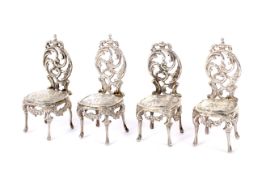 A set of four minature silver French style chairs.