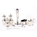 An assortment of silver, including salt and pepper shakers, mustard pots spoons and a bud vase,