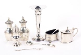 An assortment of silver, including salt and pepper shakers, mustard pots spoons and a bud vase,