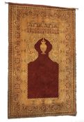 A 20th century wall hanging red ground directional prayer rug. With geometric foliate borders, W127.