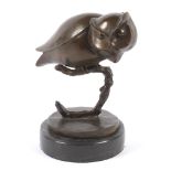 A 20th century bronze sculpture of an owl on a black marbled circular base.