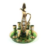 An Italian gilt and enamelled green glass decanter, stopper, circular tray and six glasses.