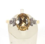 A yellow topaz dress ring. The centre stone flanked by six diamonds.
