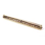 A mid-20th century gold and diamond bar brooch in Art Deco style.