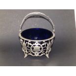 An openwork silver swing handled sugar basket, decorated neoclassical urns, with blue glass