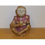 A novelty ceramic figure of a seated monkey holding a pipe, 7.25" high - a/f.