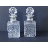 A cased pair of small modern square cut glass decanters with Mappin & Webb silver collars -