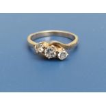 A three stone diamond crossover set ring, the central stone of approximately 4mm diameter, on '18ct'