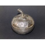 A white metal covered box of apple shape with stalk finial, embossed lobed panels, 3.4" diameter.