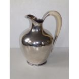 A Sterling silver pitcher, of plain design with ivory loop handle with gadrooned footrim, 10" high.