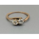A two stone old cut diamond crossover set ring in yellow metal. Finger size M/N.