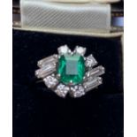 A 1970's certified natural emerald & diamond cluster ring, the central claw set rectangular cut