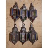 A set of six North African metal frame hanging lanterns fitted with coloured glass panels, 19" high.