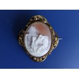 A Victorian oval pinchbeck cameo brooch, carved with a scene depicting a young woman resting at a