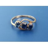 A three stone crossover set sapphire ring on yellow metal shank. Finger size J.