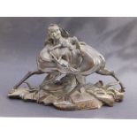 An antique signed Oriental bronze group depicting a monkey holding a leaf as shade, recumbent on the