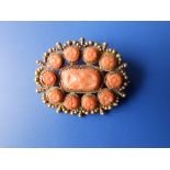 A coral set openwork oval brooch of cluster design, each claw set coral carved with a flowerhead -