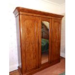 A Victorian mahogany triple section wardrobe, the projecting cornice over a central round arch