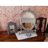 An antique style silvered metal oval dressing table mirror flanked by two cherubs, 21" high and a