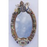A 19thC Meissen style porcelain mirror, the oval frame profusely flower encrusted, surmounted by two