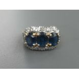 A three stone sapphire & diamond cluster ring, the three claw set oval sapphires of total