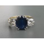 A modern three stone sapphire & diamond ring, the central oval claw set sapphire weighing