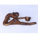 A modern carved wooden seated female figure, holding a bowl in her elongated outstretched arm, 24"