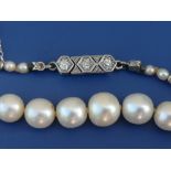 An Edwardian certified graduated natural saltwater pearl necklace with diamond set clasp, comprising